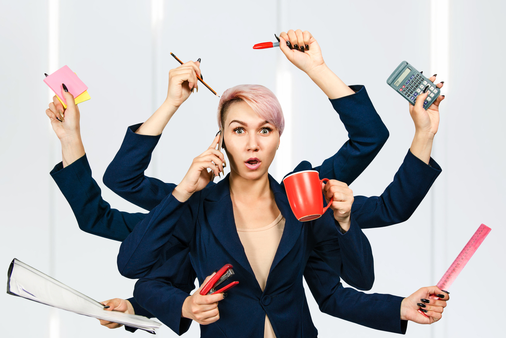 Harried businesswoman with 4 sets of hands all doing different things