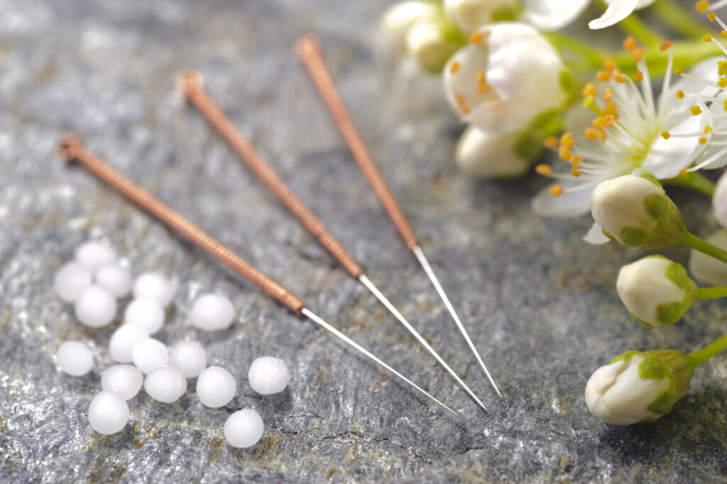 a photograph of acupuncture needles  alongside some pretty flowers