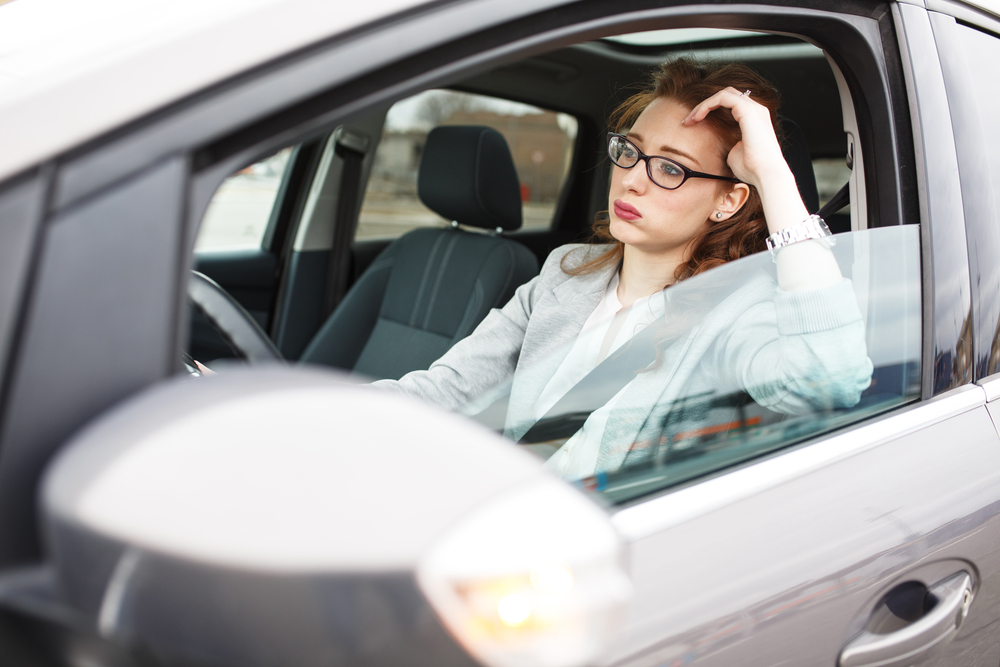 Young professional woman in car stalled in traffic, anxious and stressed out due to delay